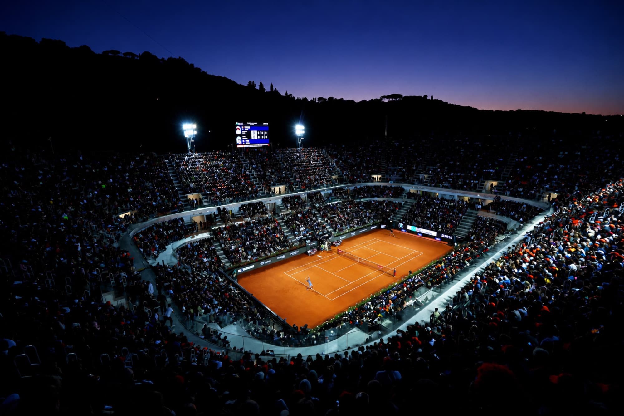 Estádio do Foro Itálico à noite, com a quadra de saibro iluminada e a arquibancada lotada
